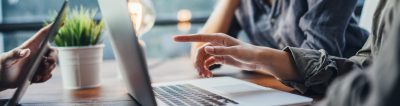 An employee hand pointing at a laptop screen